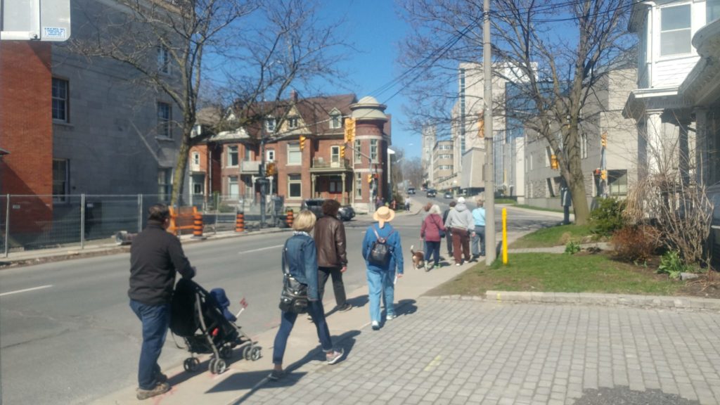 Ten people with their backs to the camera walking up a stretch of Johnson Street between stops 3 and 4 on the tour.